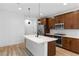 Modern kitchen features stainless appliances, an island and wood cabinets with light plank flooring at 11756 Emerald Lake Ave, Las Vegas, NV 89138