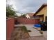 A backyard view with a red brick wall, desert landscaping, a patio area, and minimal yard maintenance at 1732 Yellow Rose St, Las Vegas, NV 89108