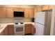 Functional kitchen features white appliances, wood cabinets, and tiled countertops for easy maintenance at 1947 Cutlass Dr # 0, Henderson, NV 89014
