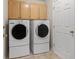 Bright laundry room features modern washer and dryer units, as well as wooden storage cabinets at 2292 Cassatt Dr, Henderson, NV 89074