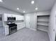 Modern kitchen boasts stainless steel appliances, light countertops, and sleek white cabinetry with gray wood flooring at 2990 La Canada St, Las Vegas, NV 89169