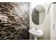 A modern half-bathroom with decorative mosaic tile on the wall and an eye-catching circular mirror at 3096 Beaux Art Ave, Henderson, NV 89044