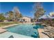 A backyard oasis featuring a large swimming pool, hot tub, and shaded seating areas, perfect for outdoor relaxation at 537 Tuscany View St, Las Vegas, NV 89145