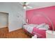 Bedroom with hardwood floors and a pink accent wall. Features a decorative bed frame at 6404 Extreme Shear Ave # 103, Henderson, NV 89011