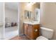 Bathroom with a wooden vanity, white countertop, and a large mirror, conveniently located near a bedroom at 6895 Kelp Ledge Ct, Las Vegas, NV 89131