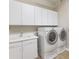 Functional laundry room with white cabinetry, a utility sink, and modern washer and dryer at 6895 Kelp Ledge Ct, Las Vegas, NV 89131