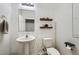 Half-bathroom featuring geometric accent wall, floating shelves, pedestal sink, and toilet at 7900 Eastern Elk St, Las Vegas, NV 89149