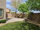 Private backyard showcasing a patio dining set, manicured artificial grass, and mature foliage at 8088 Smoking Jacket Pl, Las Vegas, NV 89166