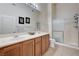 Bright bathroom featuring double sinks, wooden cabinetry, and a glass-enclosed shower at 8985 S Durango Dr # 2014, Las Vegas, NV 89113