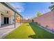 Fully landscaped backyard featuring artificial turf, covered patio, and a privacy wall at 9057 N Skye Treeline St, Las Vegas, NV 89166