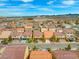Expansive aerial view of a suburban neighborhood featuring uniform homes with red tile roofs under a bright blue sky at 9768 Fox Estate St, Las Vegas, NV 89141