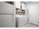 Bright laundry room features a washer, dryer, cabinets, and shelving at 9768 Fox Estate St, Las Vegas, NV 89141