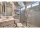 Bright bathroom features white cabinets, floating shelves, shower with glass enclosure and tile flooring at 10 Sugarberry Ln, Las Vegas, NV 89135