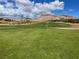 Expansive green golf course with a flag in the distance against a backdrop of mountains and blue skies at 10 Sugarberry Ln, Las Vegas, NV 89135