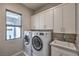This laundry room has a front load washer and dryer, gray cabinets, and a sink at 10 Sugarberry Ln, Las Vegas, NV 89135