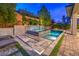 Beautiful pool and spa with a mosaic tile waterfall feature, surrounded by lush landscaping and stone pavers at 10 Sugarberry Ln, Las Vegas, NV 89135