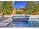 Swimming pool area with stone surround and lush landscaping and water feature wall at 10 Sugarberry Ln, Las Vegas, NV 89135