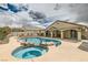 A backyard oasis featuring a pool with rock waterfall and spa surrounded by desert landscaping at 1010 Christopher View Ave, North Las Vegas, NV 89032