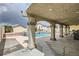 Covered outdoor living space overlooks a pool with rock waterfall features and multiple seating areas at 1010 Christopher View Ave, North Las Vegas, NV 89032