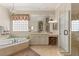 Well-lit bathroom with a large mirror, soaking tub, vanity, and glass shower enclosure at 1303 Panini Dr, Henderson, NV 89052