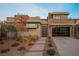 Modern home with desert landscaping, stone accents and glass garage door for great curb appeal at 18 Garden Rain Dr, Las Vegas, NV 89135