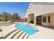 Private backyard featuring a pool, covered patio, desert landscaping and mature palm trees at 2197 Big Bar Dr, Henderson, NV 89052