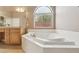 Bright bathroom featuring a large bathtub with an arched window at 2197 Big Bar Dr, Henderson, NV 89052