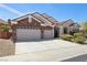 Charming home showcasing a stone facade, well-manicured landscaping, and a spacious three-car garage at 2197 Big Bar Dr, Henderson, NV 89052