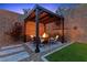 Inviting backyard pergola covered seating area featuring a cozy fire pit, comfortable seating, and lush landscaping at 2367 Ridgeline Wash St, Las Vegas, NV 89138