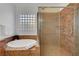 Bright bathroom featuring a soaking tub, glass block window, and separate glass-enclosed shower at 2470 Lothian St, Henderson, NV 89044