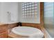 Bright bathroom showcasing a soaking tub with stylish tile surround and glass block window at 2470 Lothian St, Henderson, NV 89044