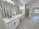 Bathroom featuring dual sinks, marble counters, white cabinets, and access to bedroom and closet at 2900 W Jaybird St, Pahrump, NV 89048