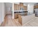 Open-concept kitchen featuring wood cabinets, a granite island, stainless steel appliances, and light wood flooring at 3359 Via Tizzoni St, Henderson, NV 89044