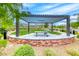 Relaxing common area with picnic tables beneath a pergola on a manicured lawn and decorative brick wall at 365 Crown Mesa Ave, Las Vegas, NV 89138