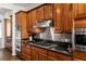 Kitchen featuring granite counters, gas cooktop, stainless hood vent and wood cabinets at 48 Panorama Crest Ave, Las Vegas, NV 89135