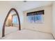 Well-lit bedroom featuring carpet, decorative curtains, and brick archway entrance to the living area at 501 Starfire Pl, Las Vegas, NV 89107