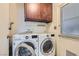 Bright laundry room with white front-loading washer and dryer, wood cabinets, and shelving at 501 Starfire Pl, Las Vegas, NV 89107