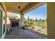 Relaxing back patio with an outdoor fireplace, lush landscaping, and greenbelt view at 5524 E San Pietro Dr, Pahrump, NV 89061