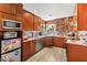 Compact kitchen featuring wood cabinets, a stainless steel dishwasher, and a microwave in a efficiently designed space at 5612 Beach Mill Way, Las Vegas, NV 89130