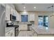 Bright kitchen with white cabinets, stainless steel appliances, a granite countertop island, and slider to outdoor space at 5697 Garriga Dr, Las Vegas, NV 89135