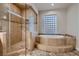 Luxurious bathroom featuring a glass shower and a large soaking tub with tile surround at 7521 Prancing Pony Ct, Las Vegas, NV 89131