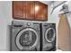 Modern laundry room with front-load washer and dryer, wooden cabinets, and an ironing board at 7860 Villa Del Fuego, Las Vegas, NV 89131