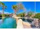 A serene pool and spa surrounded by rock features, lush palms and meticulous landscaping on a sunny day at 8348 Mountain Destiny Ave, Las Vegas, NV 89131