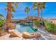 Resort-style backyard pool and spa area surrounded by lush landscaping and palm trees on a sunny day at 8348 Mountain Destiny Ave, Las Vegas, NV 89131