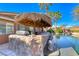 Backyard features a bar with a tiki roof next to the beautiful pool surrounded by mature palms at 8348 Mountain Destiny Ave, Las Vegas, NV 89131