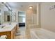 Inviting bathroom featuring a double vanity, jetted tub, and a doorway to the bedroom at 8407 Kettledrum St, Las Vegas, NV 89139