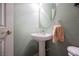 Powder room features a pedestal sink, oval mirror and neutral wall color at 8412 Starstruck Ave, Las Vegas, NV 89143