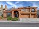 Two-story home with a three-car garage, an arched entryway, a tile roof, solar panels, and desert landscaping at 8716 Castle Hill Ave, Las Vegas, NV 89129