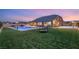 Wide backyard featuring a sparkling blue pool, covered patio, playground, and lush green lawn at 9096 Becket Ranch Ct, Las Vegas, NV 89113