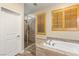 Bright bathroom features soaking tub, wood-look tile floors, privacy shutters and a glass-enclosed shower stall at 9096 Becket Ranch Ct, Las Vegas, NV 89113